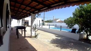 An outdoor patio with a foosball table, a small table, and a pool area with chairs. - Country house with exclusive pool (Paderne)