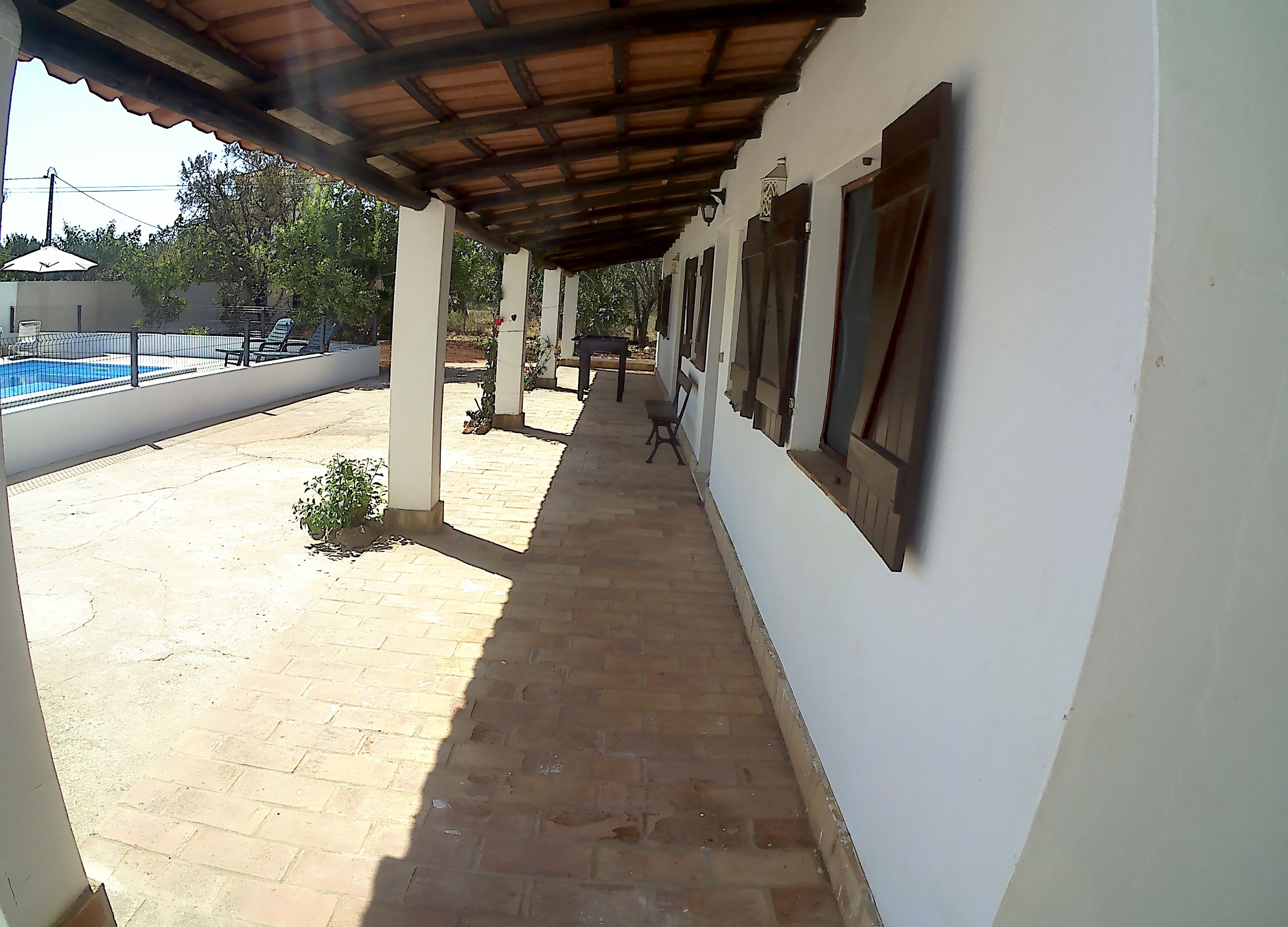 Un corridoio esterno coperto con piscina e patio in mattoni.