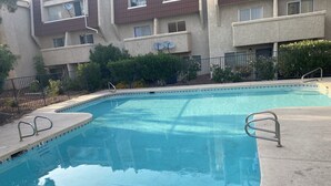 A rectangular swimming pool with a tiled edge and metal handrails.