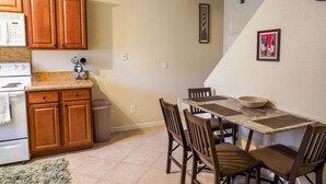A kitchen with wooden cabinets, a stove, and a dining table with chairs.