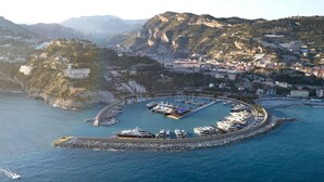 Vista aérea de un pueblo costero con un puerto deportivo, acantilados rocosos y edificios.