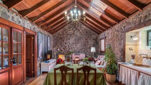 A rustic dining area with a stone wall, wooden beams, and a chandelier. - Canarian house with pool, barbecue, wifi, netflix (La Orotava)