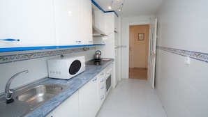 A compact kitchen with a built-in washing machine, a sink, and a stove. - Marina de la Duquesa 225 (Manilva)