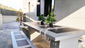 Un espace cuisine extérieur moderne, doté d’un long plan de travail et de sièges intégrés.