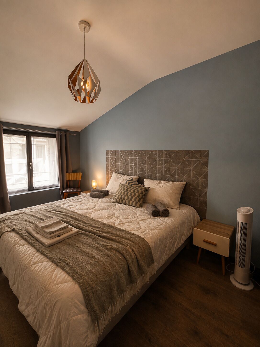 Ein Schlafzimmer mit einem großen Bett, einem Nachttisch, einer Lampe und einem Wandheizkörper.