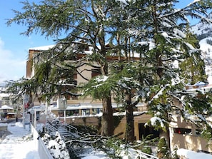 A building with multiple floors, surrounded by snow-covered trees. - Cozy studio 2 ppl, city center, WIFI, balcony, pets allowed (Brides-les-Bains)