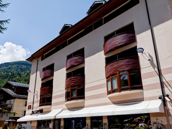 A multi-story building with large windows and balconies, featuring a striped facade and a white awning over the entrance. - Cozy studio 2 ppl, city center, WIFI, balcony, pets allowed (Brides-les-Bains)