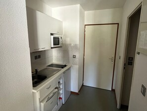 Una cocina compacta con alacenas blancas, un microondas, un lavamanos y un lavavajillas.
