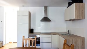 Een moderne keuken met witte kastjes, een houten eettafel en een inbouwoven.