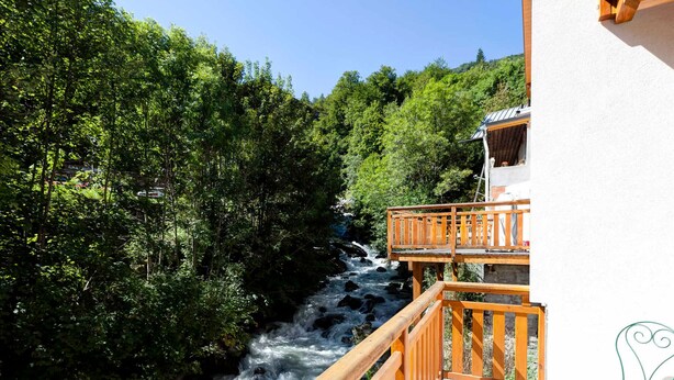 Een houten terras met een leuning, met uitzicht op een rivier, omringd door weelderige begroeiing.
