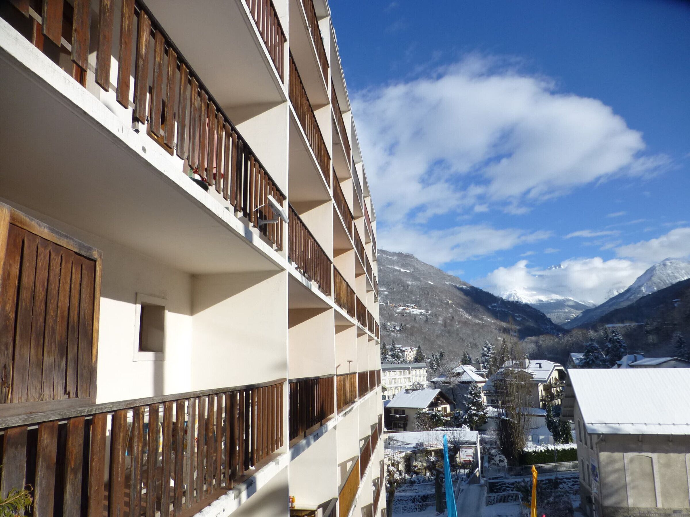 Un hôtel à plusieurs étages doté de balcons, avec une chaîne de montagnes enneigée en arrière-plan et un ciel dégagé.