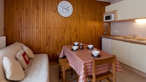 A compact living space with a wooden wall, a round table with a checkered tablecloth, and a sofa with pillows. - Studio for 5, Central, South Balcony, Elevator - Brides-les-Bains (Brides-les-Bains)