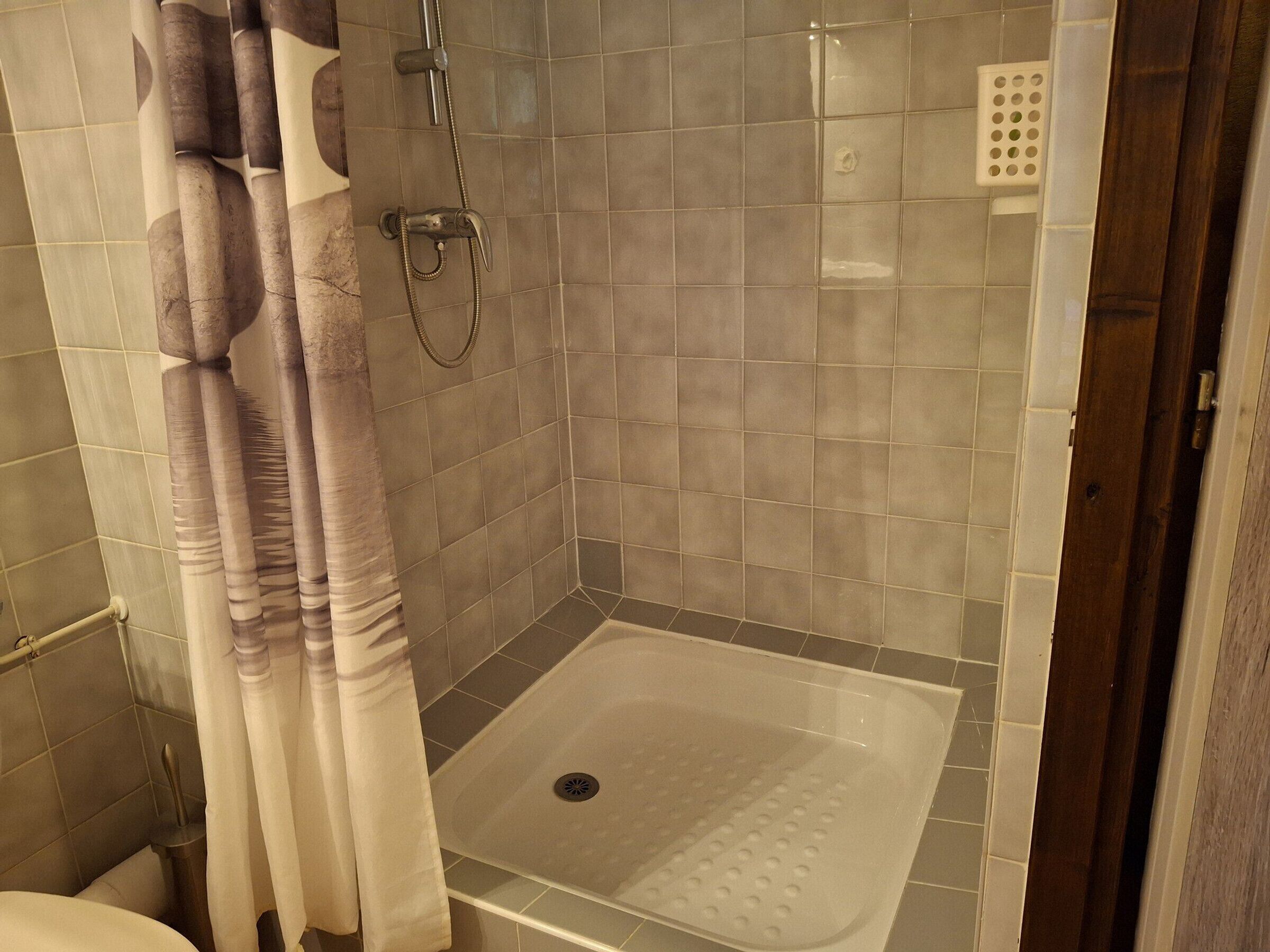 Ducha con puerta de vidrio, cabezal de ducha y desagüe.