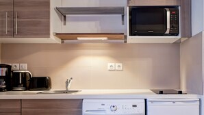 Una cocina moderna con lavadora y secadora integradas, microondas y cafetera.