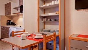 Una cocina compacta con zona de comedor, equipada con cafetera, microondas y televisor de pantalla plana.