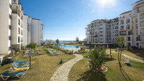 Un complexe hôtelier doté d’une piscine, de chaises longues et offrant une vue dégagée sur la mer.