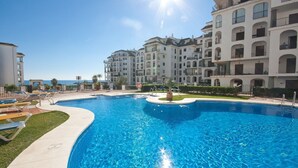 Une piscine avec des chaises longues, une bouée de sauvetage et une vue sur la mer.