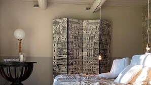 A bedroom with a large bed, a side table, a lamp, and a wall with a cityscape mural. - Prestigious estate in Ménerbes. large heated swimming pool. large landscaped grounds. (Ménerbes)