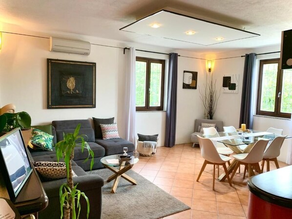 Una sala moderna con sofá, mesa de centro y comedor con sillas.