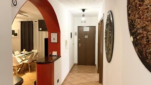 Un pasillo con un arco rojo que conduce a un comedor, una puerta con un letrero y una obra de arte colgada en la pared.