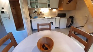 Een kleine keuken met witte kastjes, een wasmachine en een magnetron.