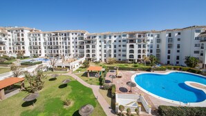 A large hotel with multiple balconies, a swimming pool, and well-maintained gardens.