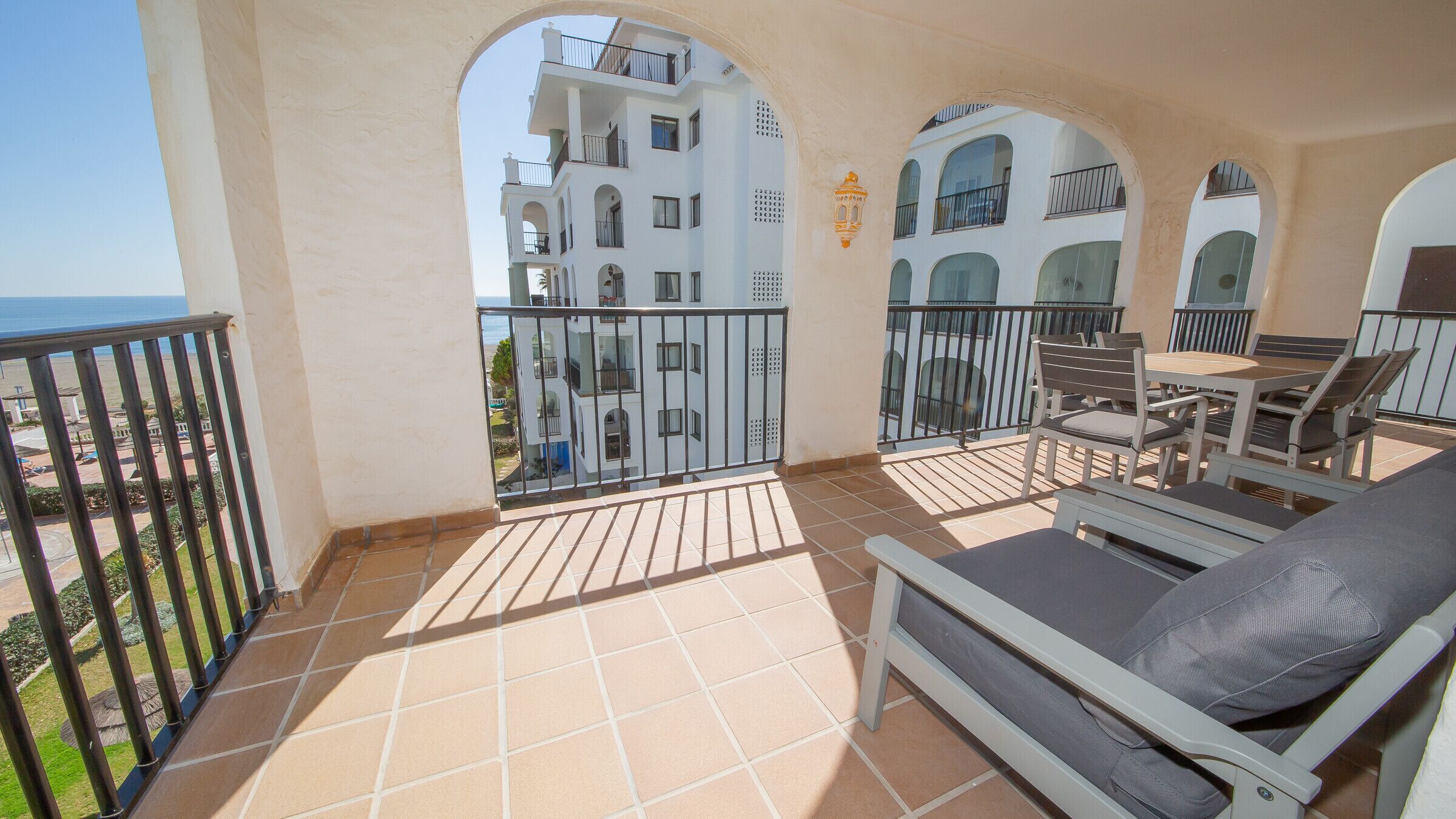A balcony with a tiled floor, a table with chairs, and a sofa.