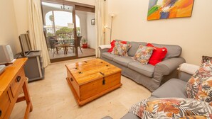 Ein Wohnzimmer mit grauem Sofa, einer Holzkiste und einem kleinen Tisch.
