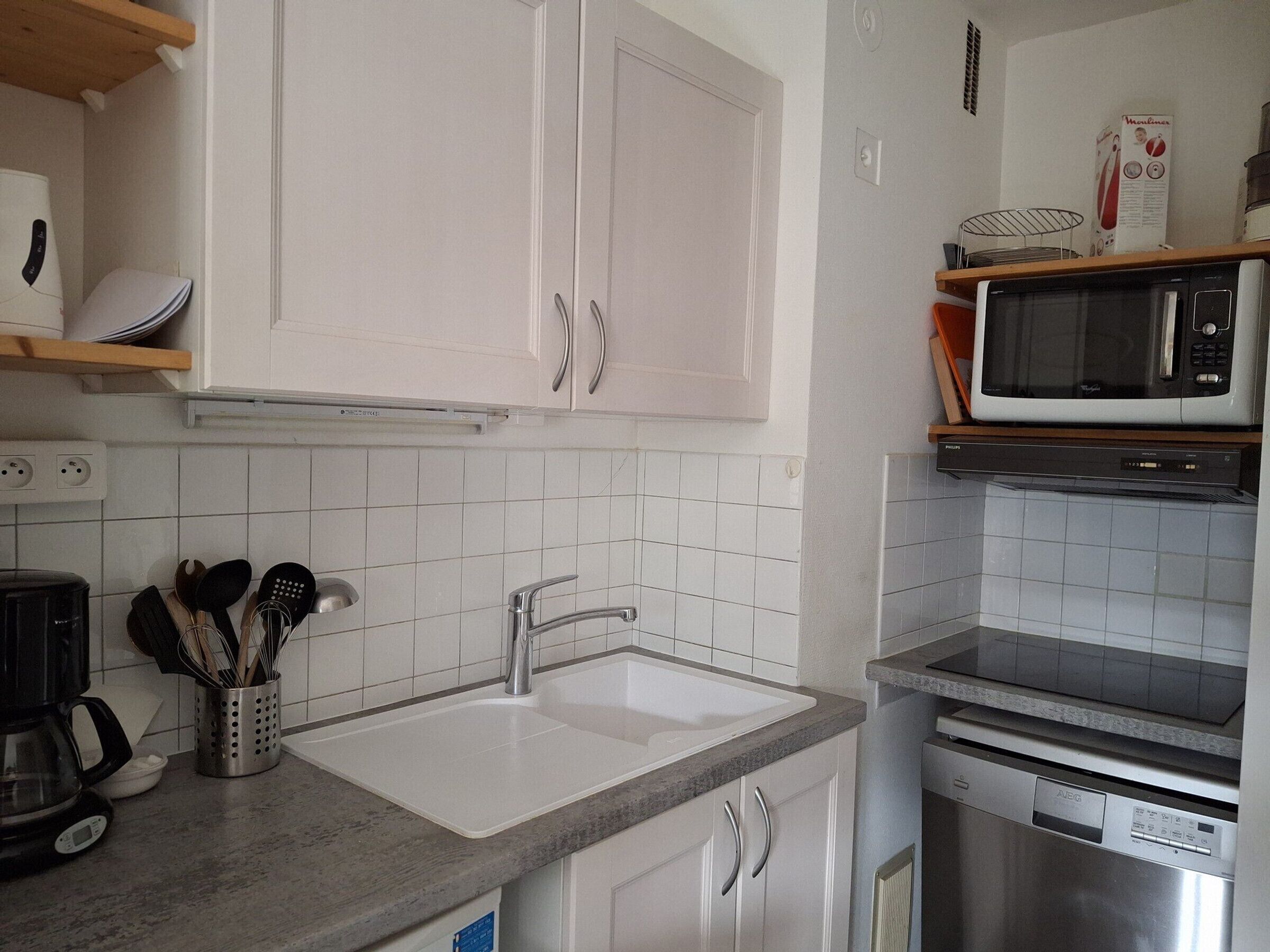 A modern kitchen with white cabinets, a stainless steel sink, a microwave, and a dishwasher.