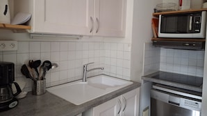 Una cocina moderna con armarios blancos, un lavamanos de acero inoxidable, un microondas y un lavavajillas.