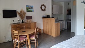 Un espacio habitable compacto con comedor, kitchenette y cama.