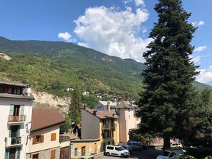 A mountain town with buildings, a prominent tree, and a clear sky.