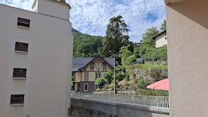 Vista de un edificio tradicional con techo inclinado y balcón, que da a un puente y un valle con vegetación.