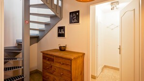 A staircase with a metal banister, a wooden dresser with drawers, a wall-mounted sign saying "hello", and a door leading to another room.