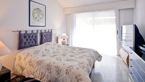 A modern bedroom with a large bed, a television, and a framed artwork on the wall.