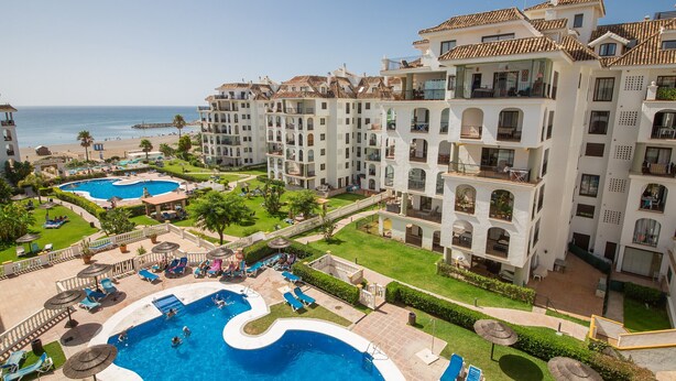 Un resort con varias piscinas, una playa y vistas al océano.