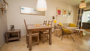 Una sala moderna con una mesa de comedor de madera, un sofá y una silla. Hay cuadros enmarcados en la pared y una lámpara sobre la mesa.