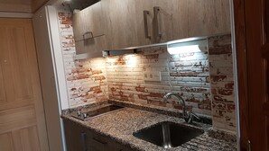 A kitchen with a granite countertop, stainless steel sink, and a brick wall backsplash. - Sunny & Ocean view Apartment (Los Cristianos)