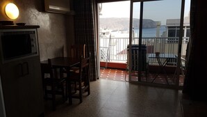 A kitchen with a dining table and chairs, a microwave, and a view of a balcony with a table and chairs. - Sunny & Ocean view Apartment (Los Cristianos)