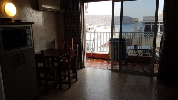 A kitchen with a dining table and chairs, a microwave, and a view of a balcony with a table and chairs. - Sunny & Ocean view Apartment (Los Cristianos)