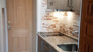 A compact kitchen with a wooden door, granite countertops, and a brick backsplash. - Sunny & Ocean view Apartment (Los Cristianos)