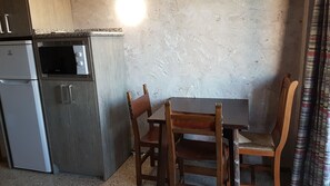 Enjoy cooking in this kitchen with microwave and refrigerator, dining table, and two chairs.