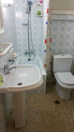 Bathroom features a bathtub, sink, and toilet, with a showerhead mounted on the wall.