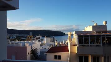 A coastal cityscape with buildings, a clear sky, and a mountain in the background.