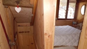 Um quarto de madeira com uma cama, uma janela e uma porta.