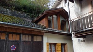 Edifício tradicional com fachada de madeira, porta de garagem visível e pequena entrada com janela.