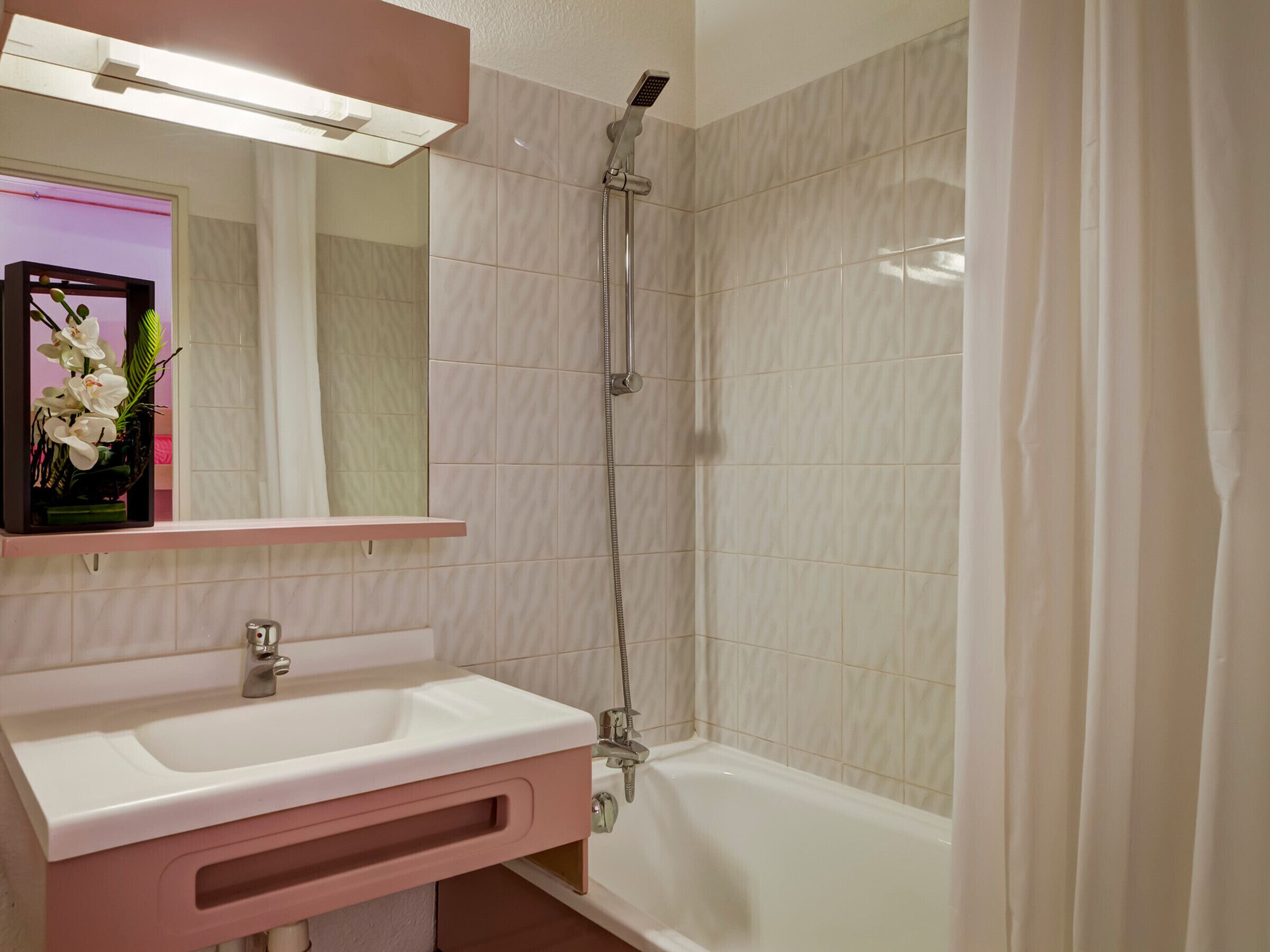 A bathroom with a sink, mirror, shower, and bathtub.