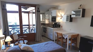 A compact hotel room with two beds, a kitchenette, a dining area, and a balcony with outdoor furniture. - Comfortable studio 28m², 4 people, pets allowed, parking, wifi (Brides-les-Bains)