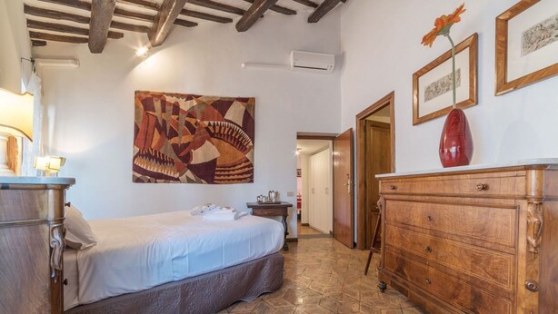 A bedroom with a bed, a wooden dresser, a wall-mounted air conditioner, and a geometric patterned artwork. - 3 bedrooms apartment in Navona area - AirConditioning, Wifi, Washing Machine (Roma)