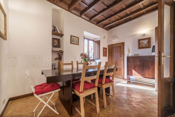 A dining area with a wooden table and chairs, a white folding chair, and a wooden floor.
